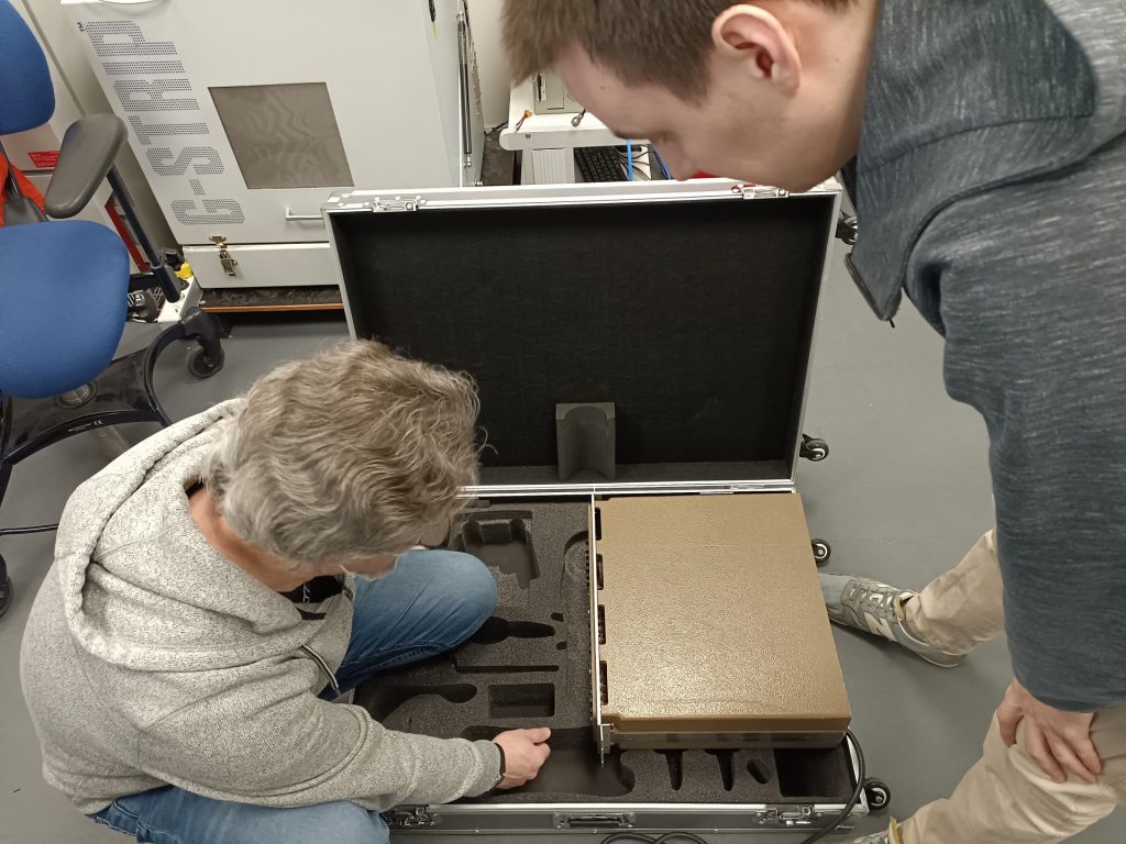 Hervé et Arthur découpent la mousse d'une grande mallette de transport professionnelle pour y adapter les formes de notre Micral N